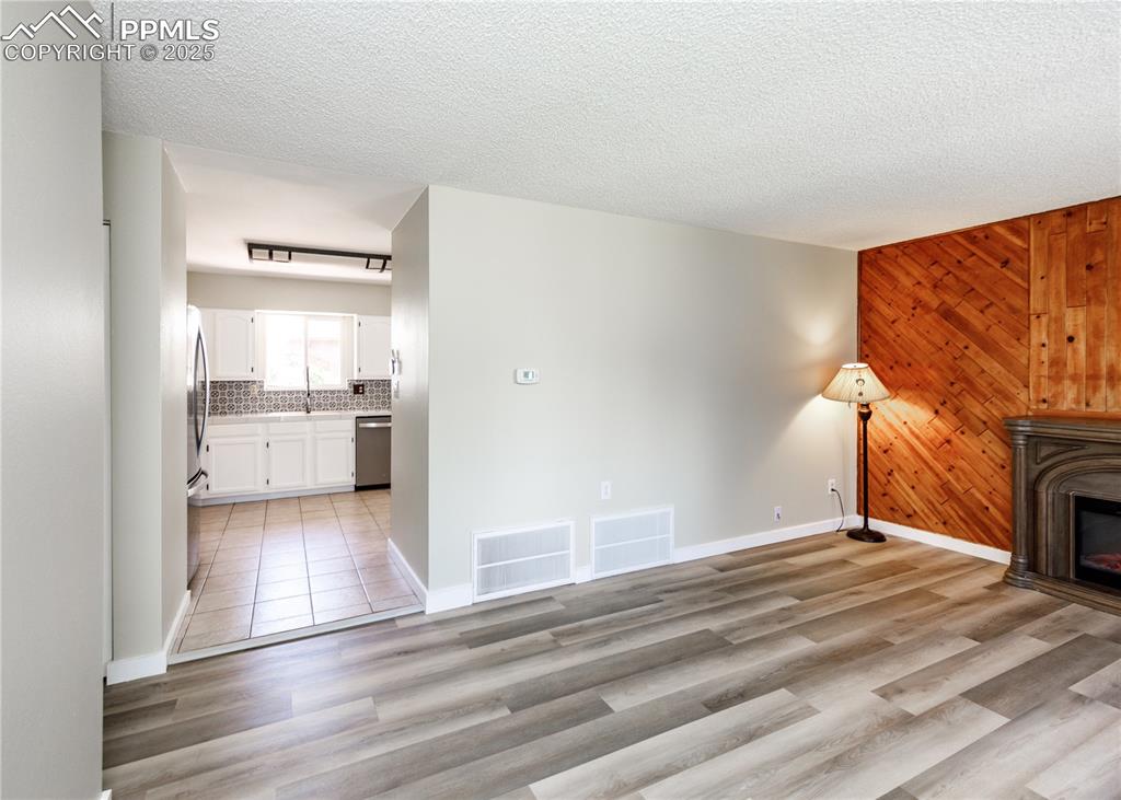 Image 9 of 48: Unfurnished living room with wood walls, a glass covered fireplace, light w