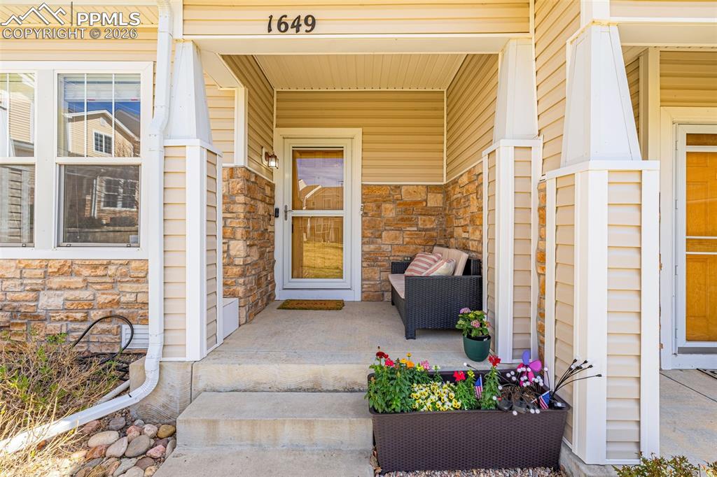Caption: Covered front entrance featuring decorative stone veneer, durable siding, and concrete steps