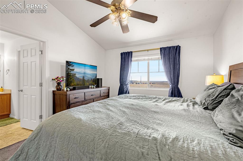 Image 11 of 29: Vaulted ceiling bedroom featuring a ceiling fan, a window with exterior vis
