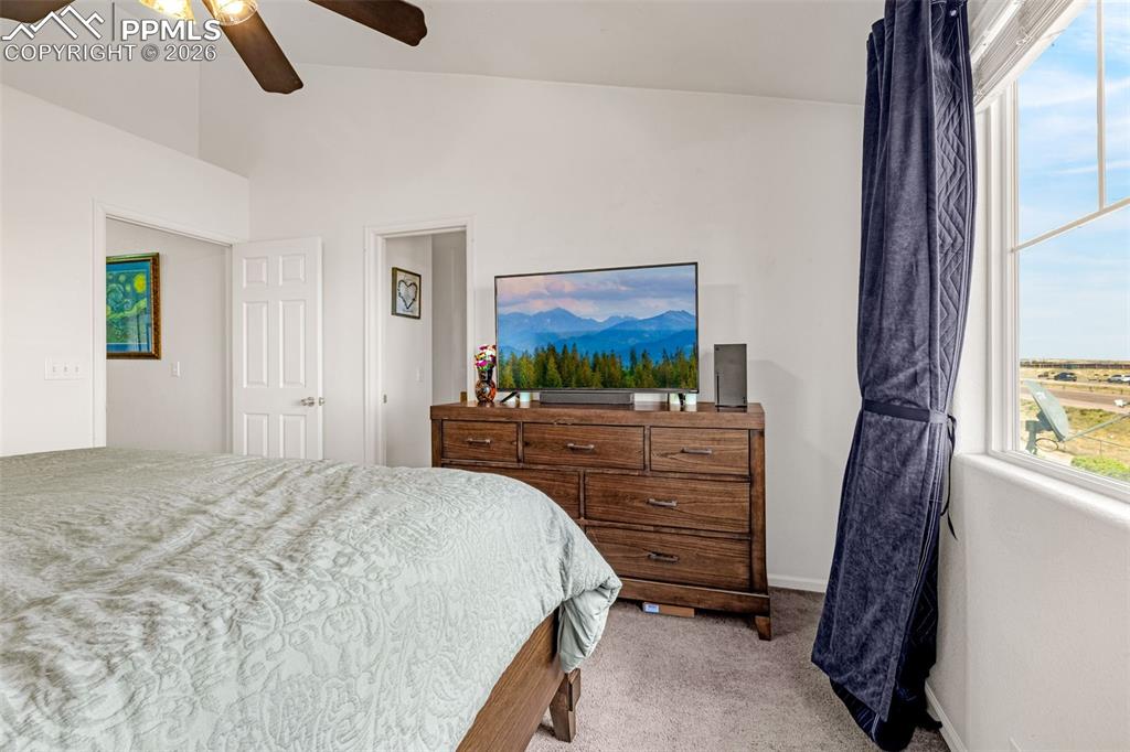 Image 12 of 29: Carpeted bedroom featuring vaulted ceilings, a ceiling fan, and a large win