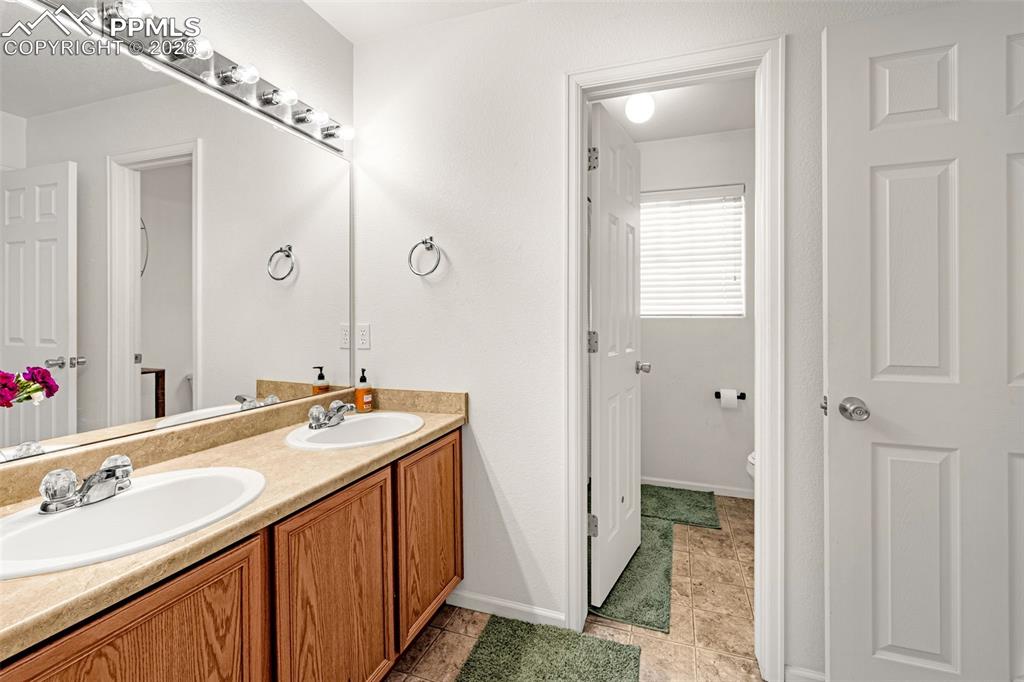Image 15 of 29: Bathroom vanity featuring a dual sink, laminate countertop, and wood-finish