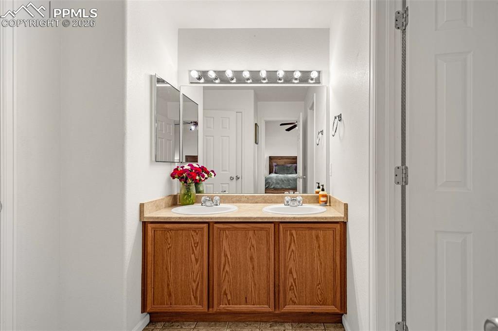 Image 16 of 29: Dual sink vanity with wood-finish cabinetry and a light-toned countertop