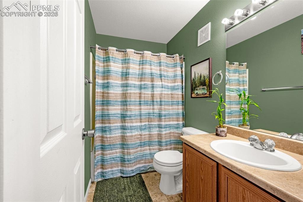 Image 19 of 29: Bathroom featuring a vanity with wood-finish cabinetry, a single basin sink