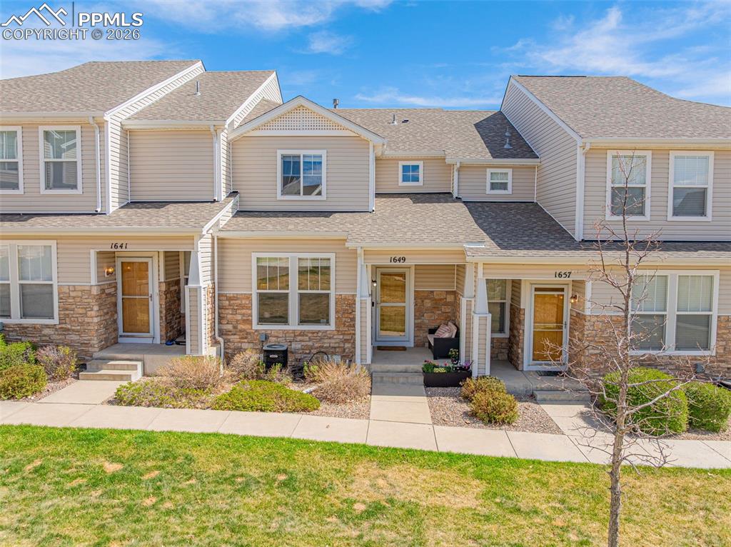 Image 2 of 29: Townhome entry featuring light-colored siding and a stone-veneer accent