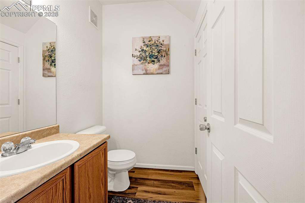 Image 21 of 29: Bathroom featuring a wood-finish vanity with a light-toned countertop and a