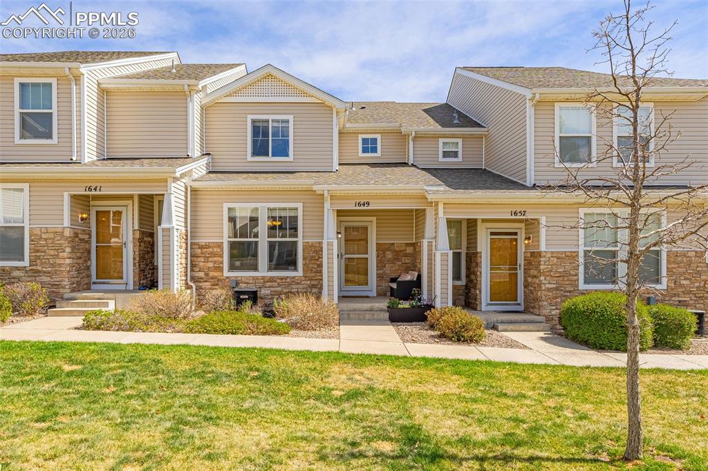 Image 25 of 29: Townhouse exterior featuring light-colored siding and stone veneer accents
