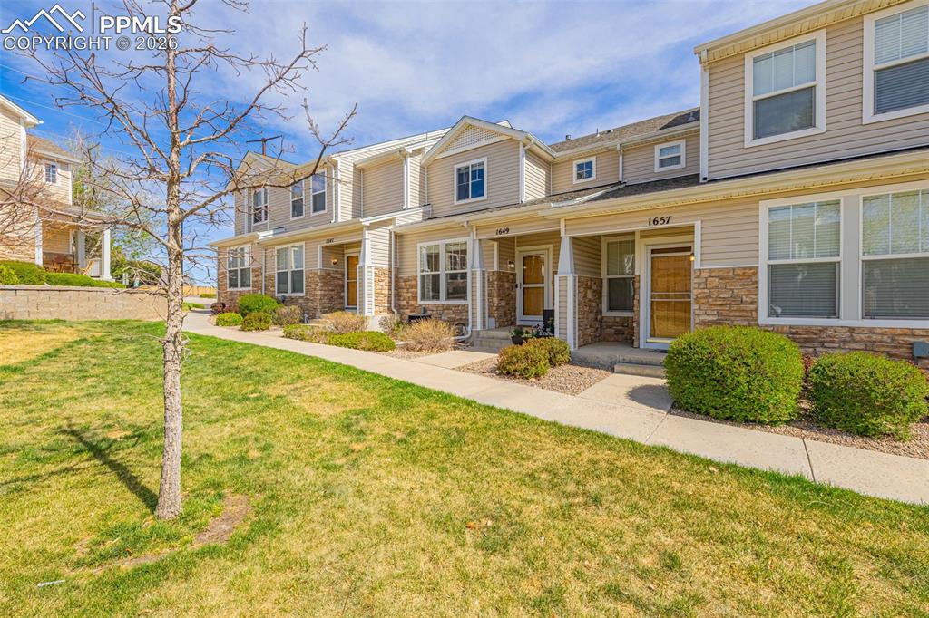 Image 26 of 29: Exterior facade featuring light-toned siding and stacked stone accents