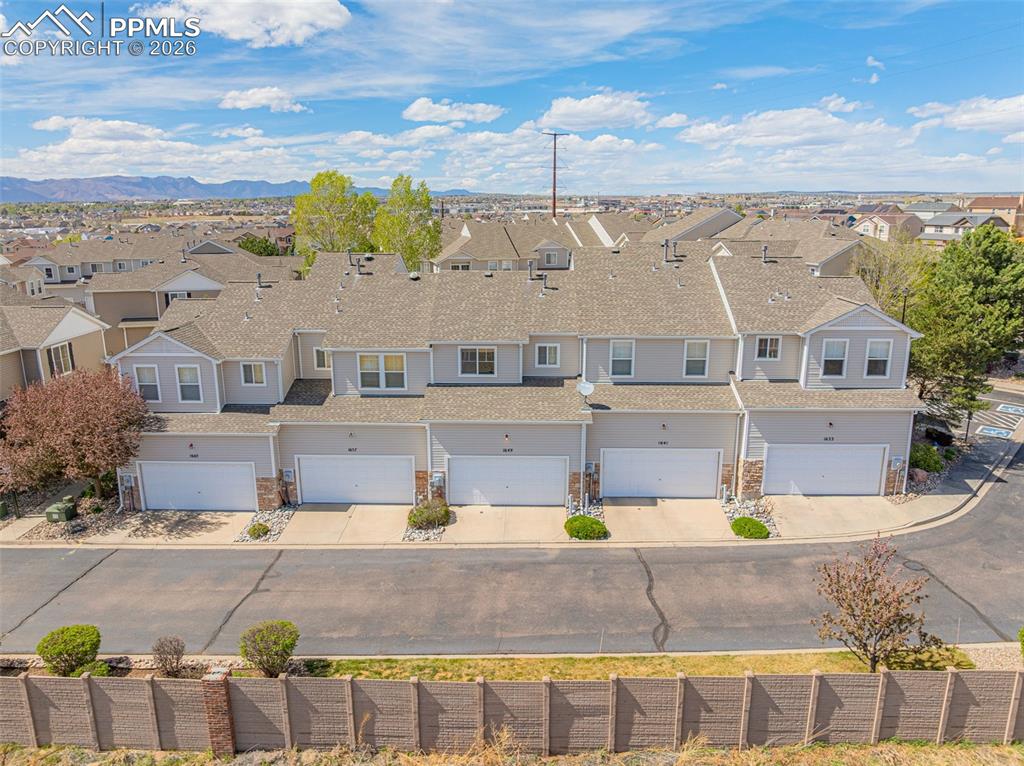 Image 3 of 29: Townhome complex featuring attached garages, stone facade accents, backing 