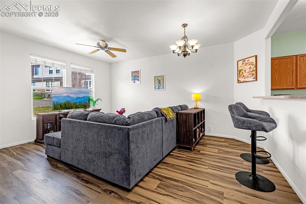 Image 7 of 29: Living area featuring wood-finish flooring, a ceiling fan, and a multi-ligh