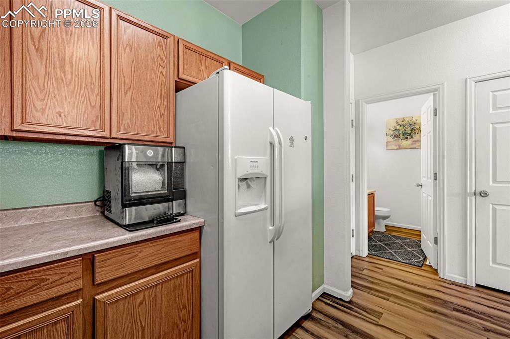 Image 9 of 29: Kitchen area featuring wood-finish cabinetry, a white side-by-side refriger