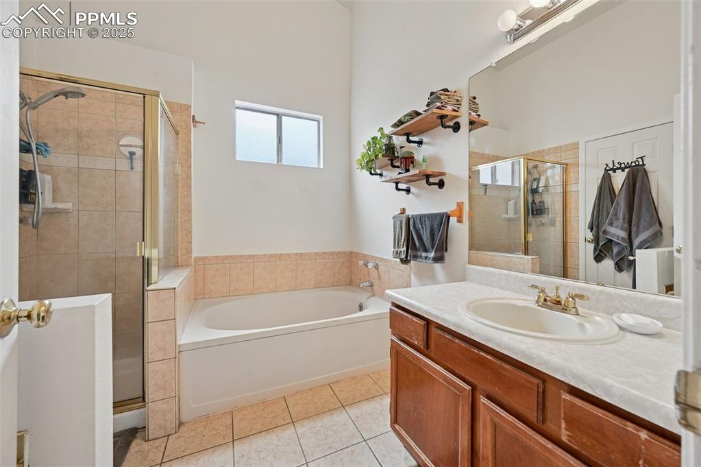 Image 13 of 27: Bathroom with vanity, a garden tub, light tile patterned flooring, and a st