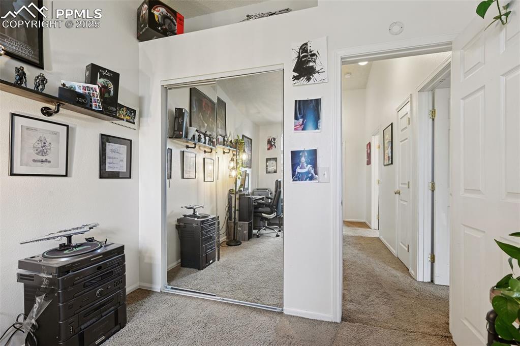 Image 15 of 27: Hallway with a desk and light colored carpet