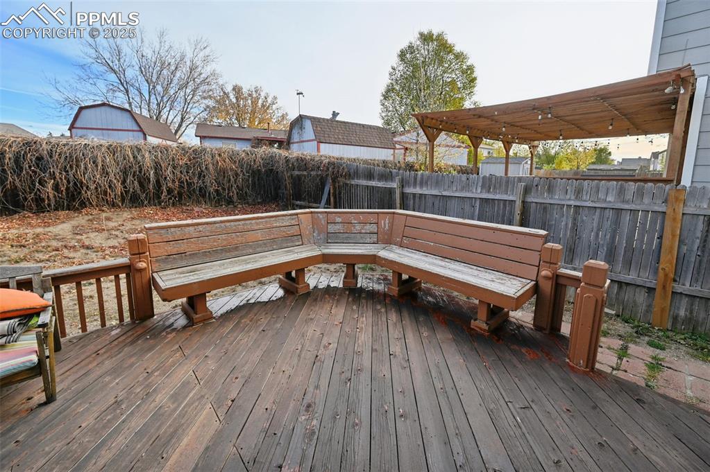 Image 23 of 27: Wooden terrace with a fenced backyard