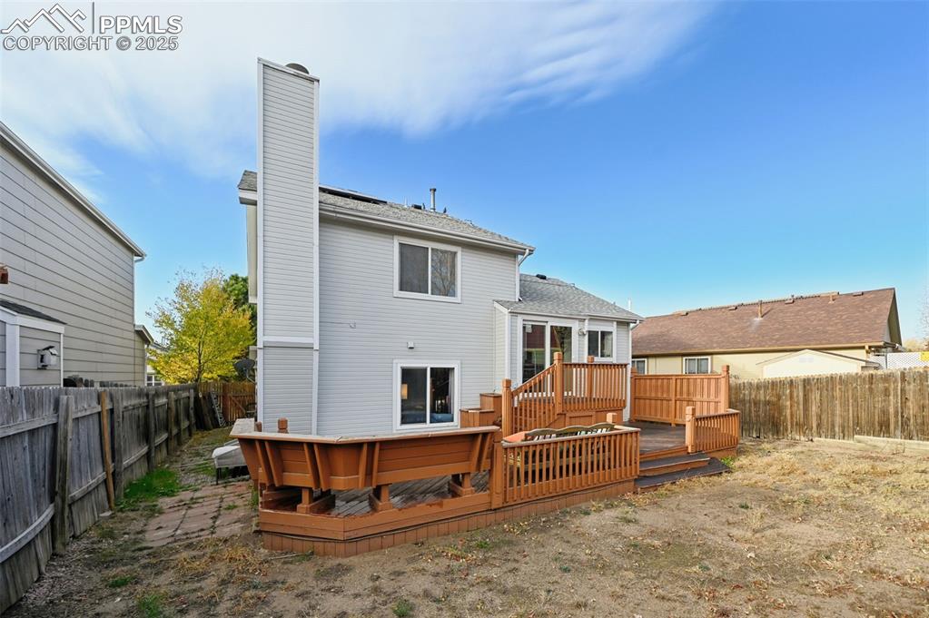 Image 25 of 27: Back of house with a chimney, a fenced backyard, a wooden deck, and a shing
