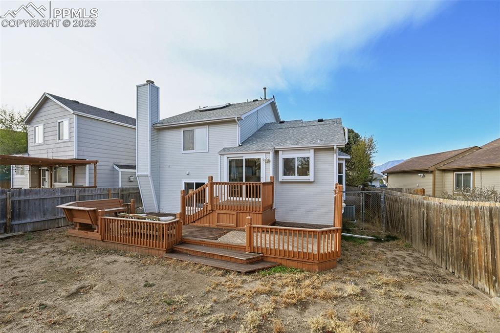 Image 27 of 27: Rear view of house featuring a fenced backyard, a wooden deck, and a shingl