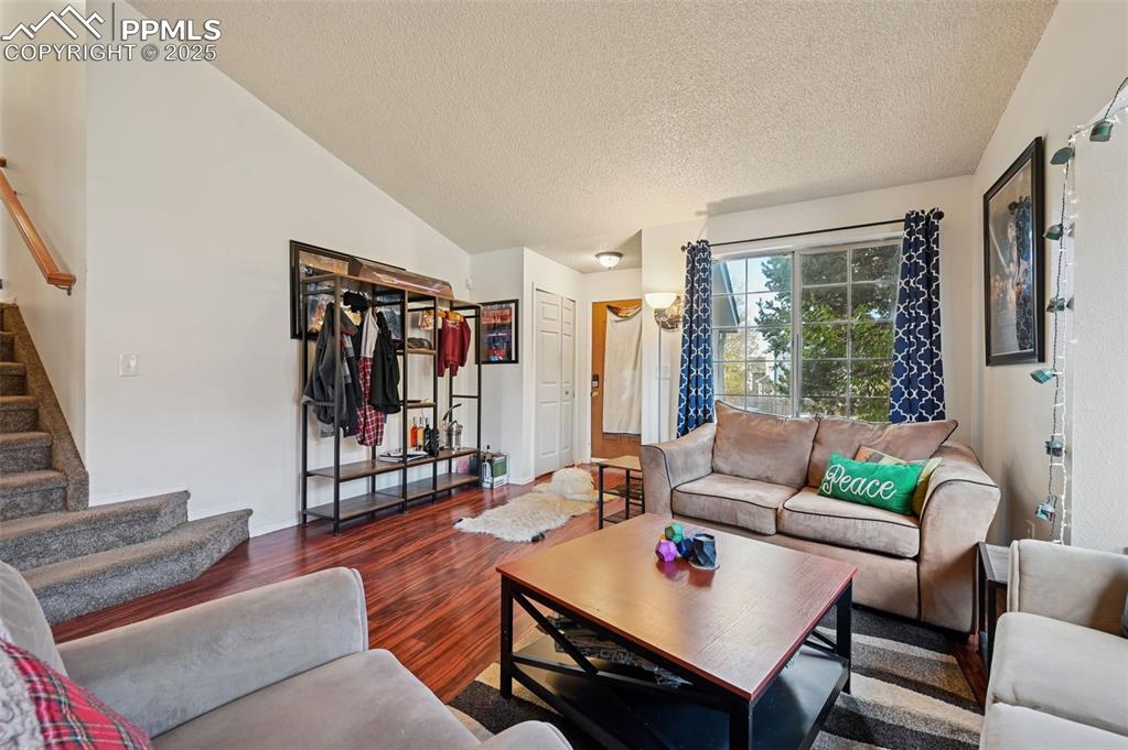 Image 5 of 27: Living area featuring wood finished floors, stairway, a textured ceiling, a