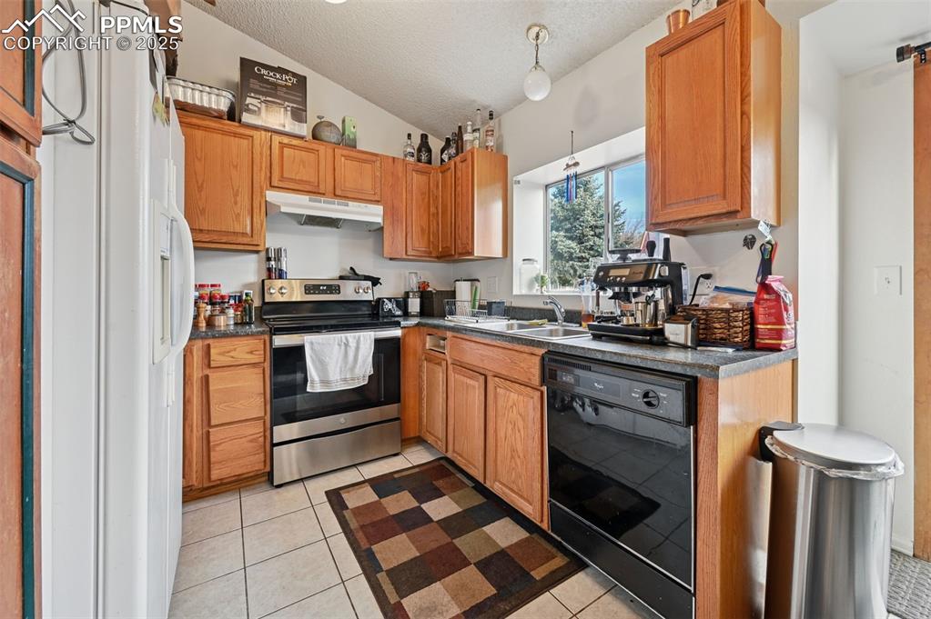 Image 8 of 27: Kitchen with dark countertops, stainless steel range with electric stovetop
