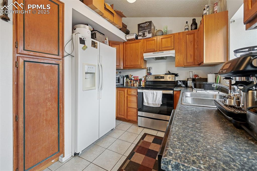 Image 9 of 27: Kitchen featuring light tile patterned flooring, stainless steel range with