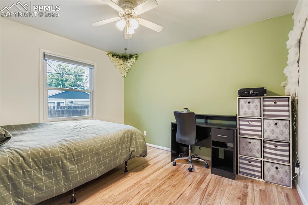 Image 13 of 22: Bedroom featuring wood finished floors, a ceiling fan, and an office area