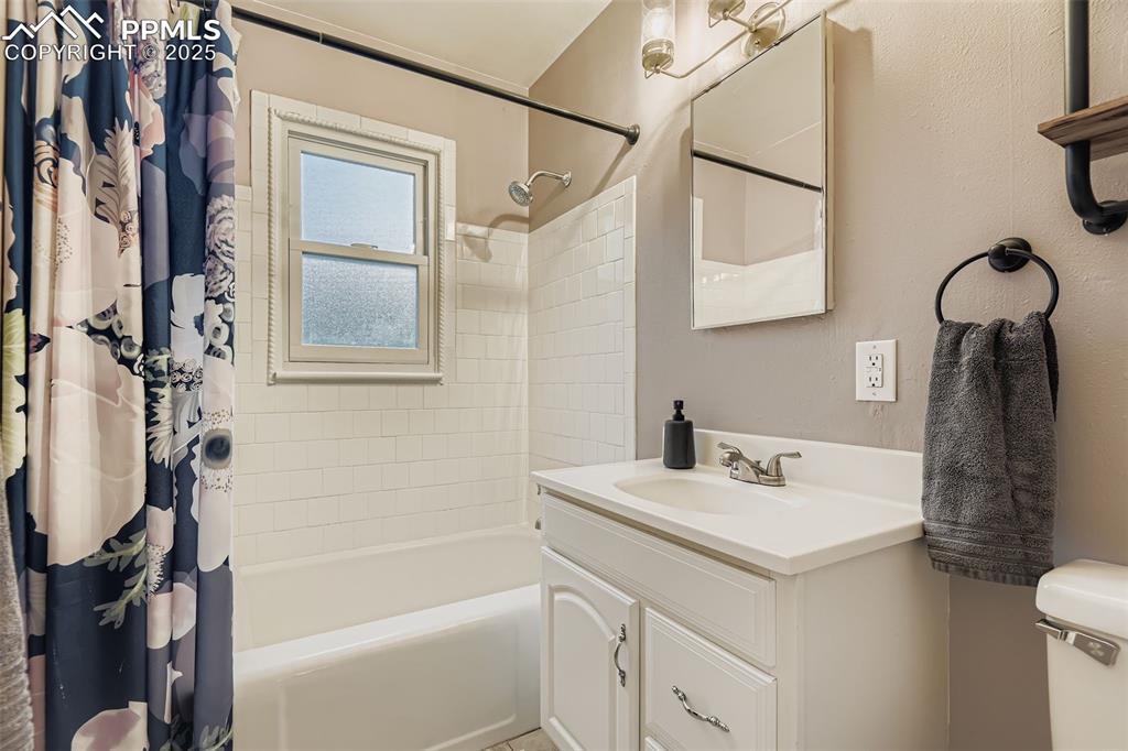 Image 15 of 22: Full bathroom featuring shower / bath combination with curtain and vanity
