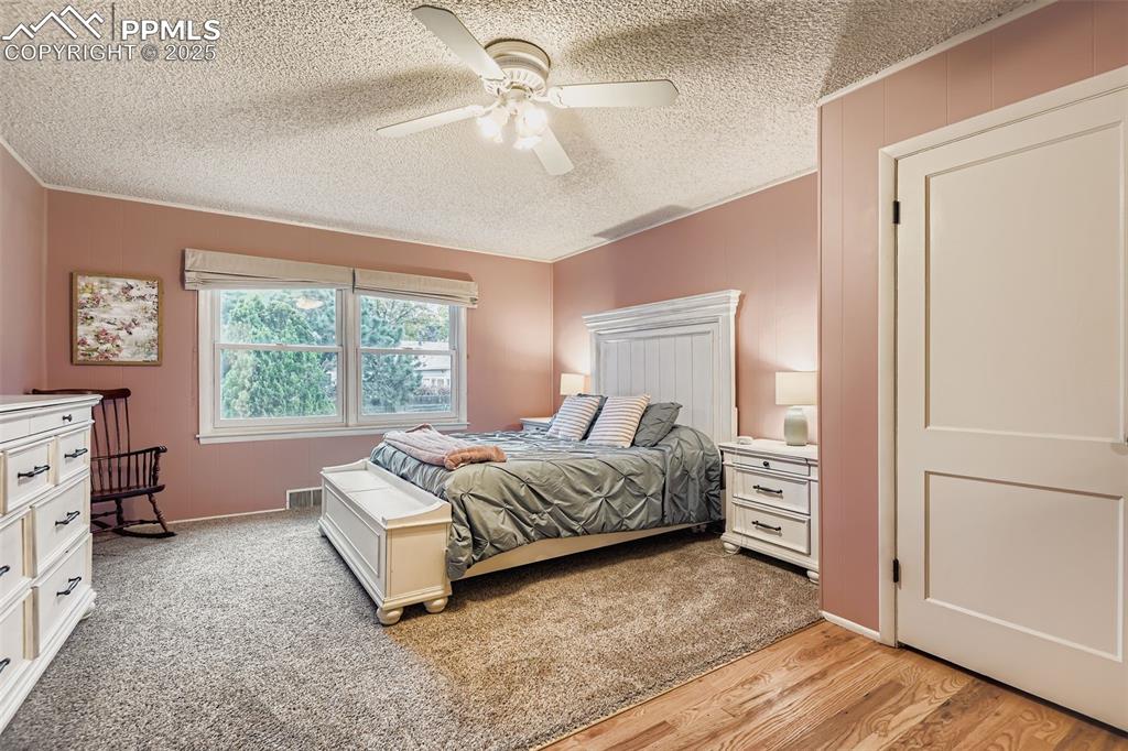 Image 16 of 22: Bedroom featuring a ceiling fan, light wood finished floors, a textured cei