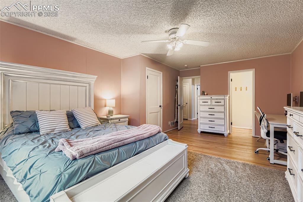 Image 17 of 22: Bedroom with light carpet, ceiling fan, an office area, a textured ceiling,