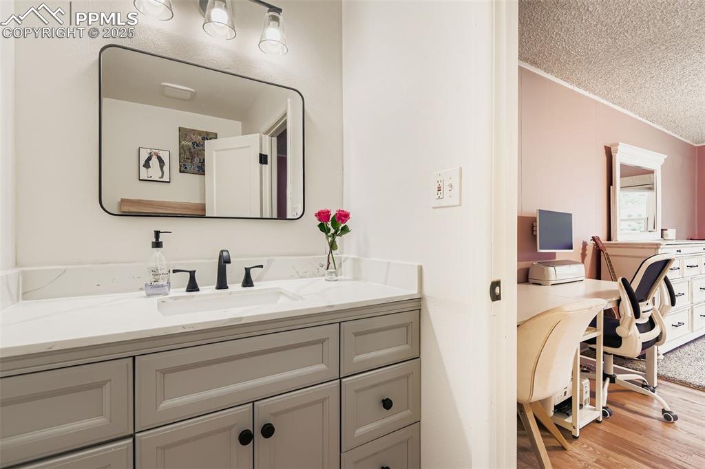 Image 18 of 22: Bathroom with light wood finished floors, a textured ceiling, vanity, and o