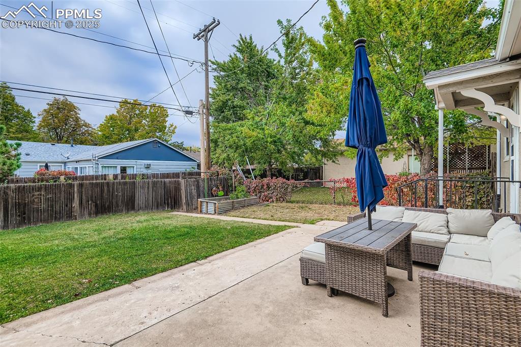 Image 19 of 22: Fenced backyard with outdoor lounge area and a patio