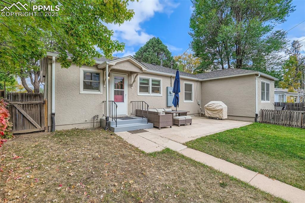 Image 21 of 22: Back of property featuring stucco siding, a gate, a patio area, an outdoor 