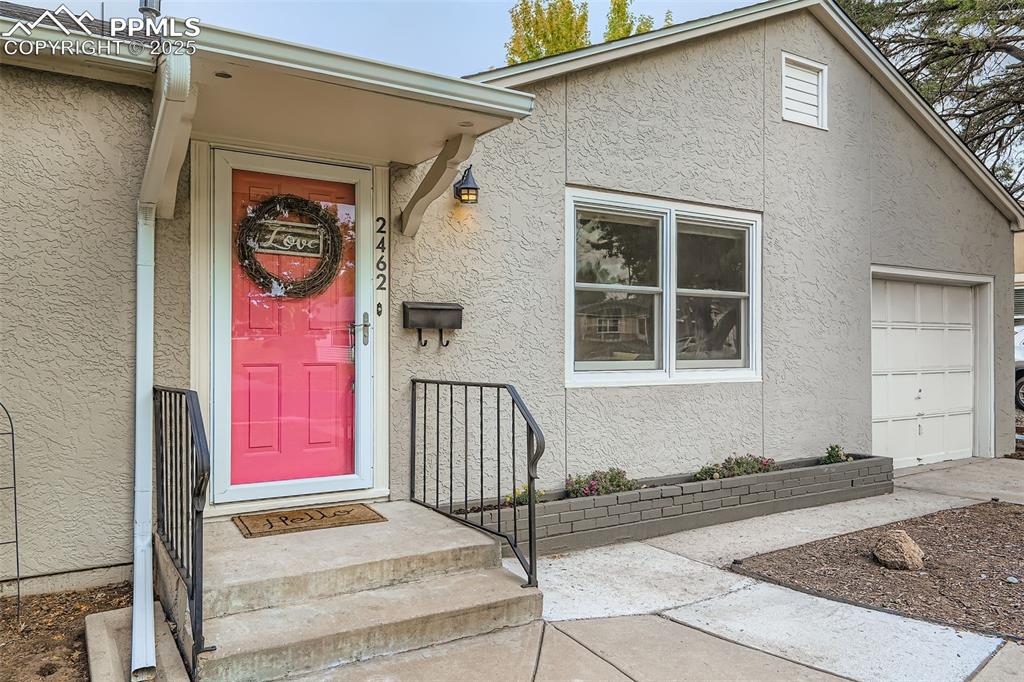 Image 3 of 22: Doorway to property with stucco siding and a garage