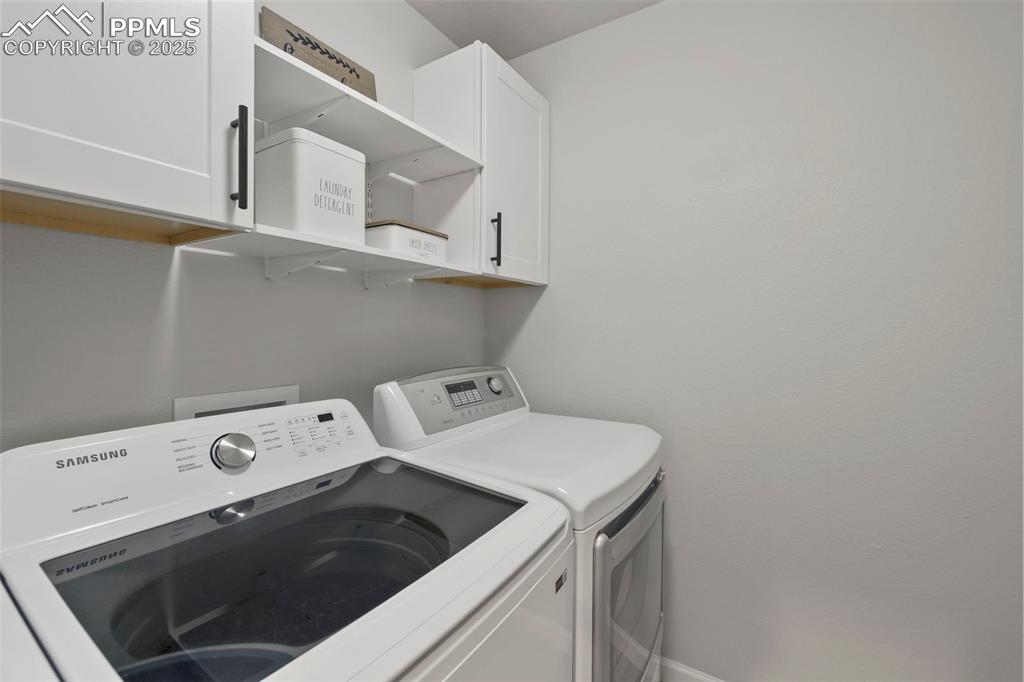 Image 18 of 24: Laundry room featuring washer and clothes dryer and cabinet space