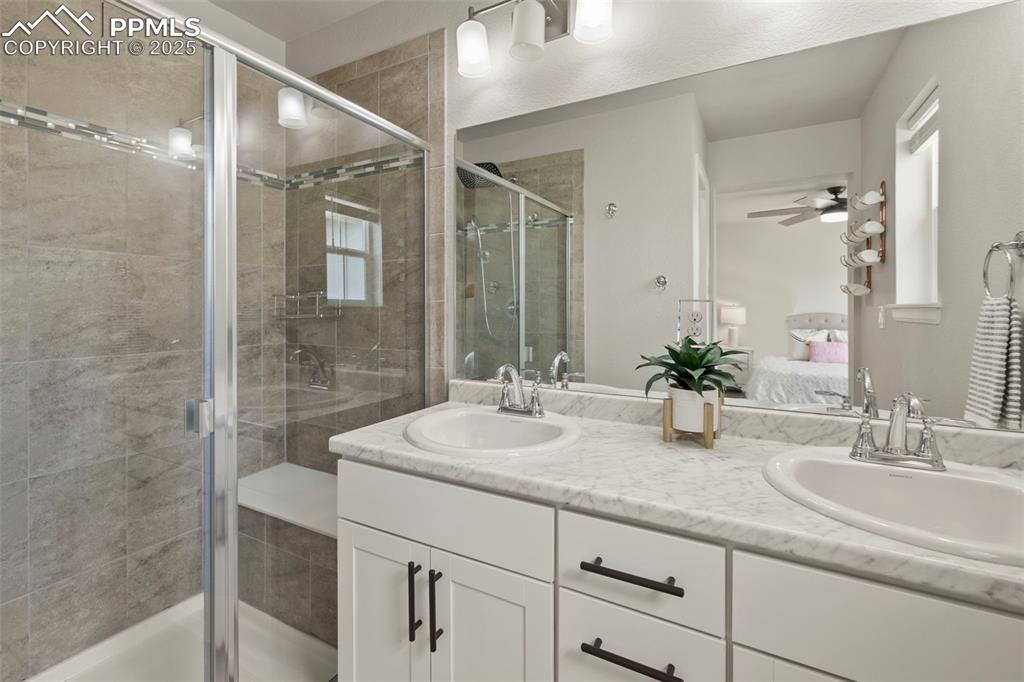 Image 23 of 24: Ensuite bathroom featuring double vanity, a stall shower, and ceiling fan