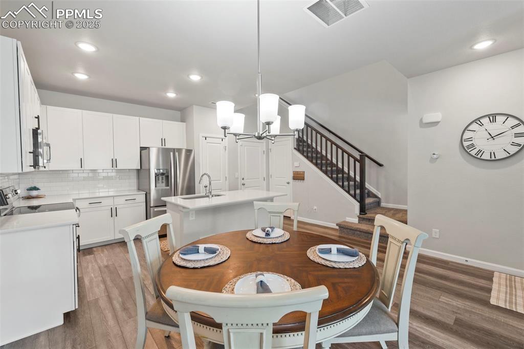 Image 6 of 24: Dining room with a chandelier, stairs, light wood-style floors, and recesse