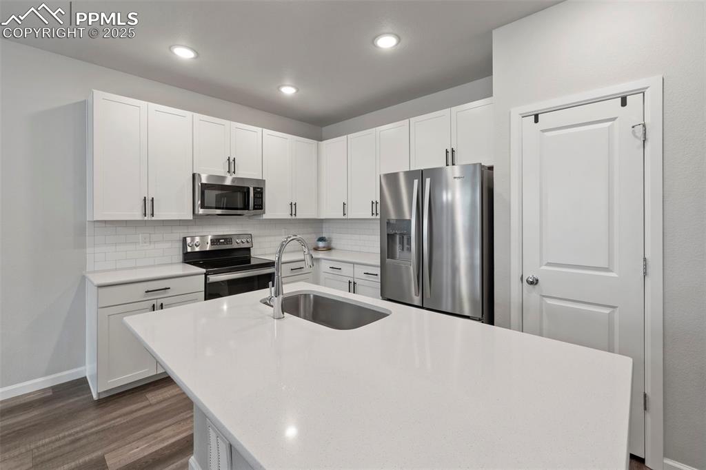 Image 8 of 24: Kitchen with appliances with stainless steel finishes, dark wood-style floo