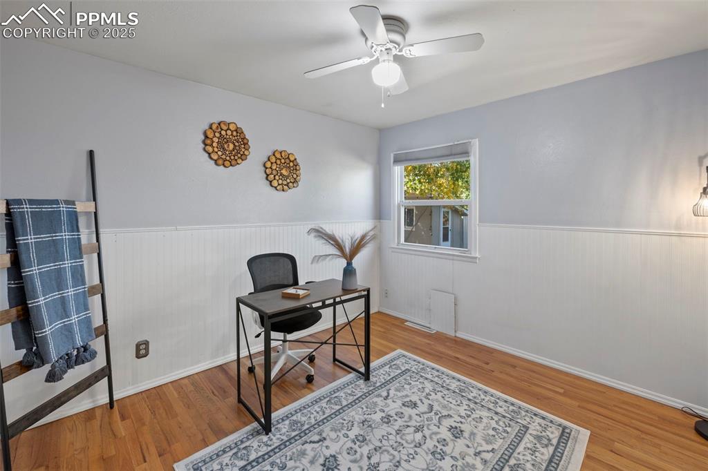 Image 12 of 30: Office with wainscoting, light wood-style flooring, and ceiling fan