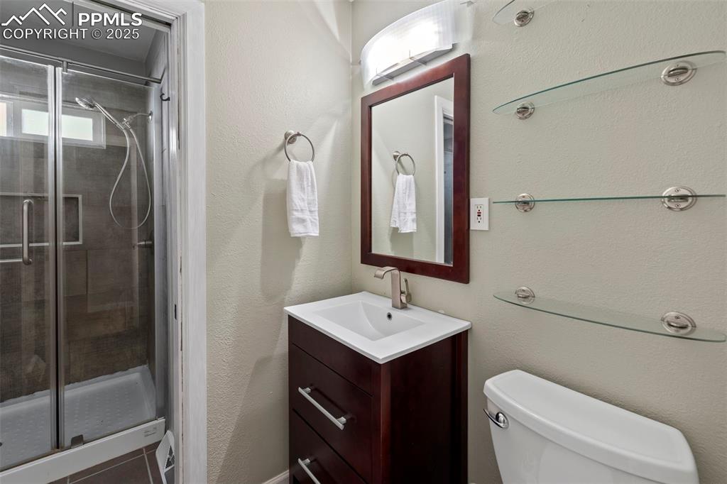 Image 13 of 30: Bathroom featuring a shower stall, vanity, a textured wall, and tile patter