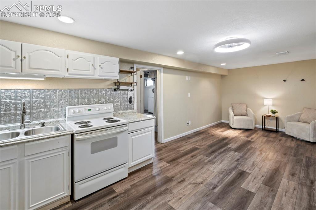 Image 17 of 30: Kitchen featuring white cabinetry, white electric stove, light countertops,