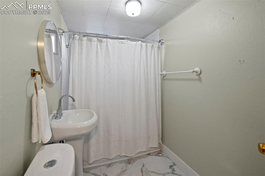 Image 19 of 30: Full bathroom featuring shower / bath combo with shower curtain, a textured