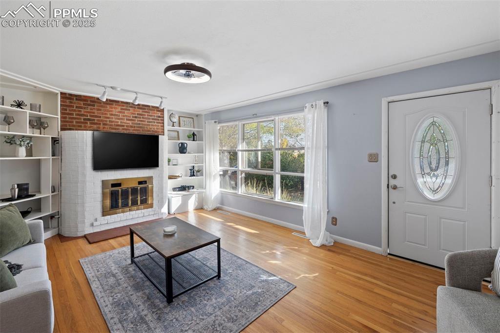 Image 2 of 30: Living room featuring light wood-style floors, a brick fireplace, built in