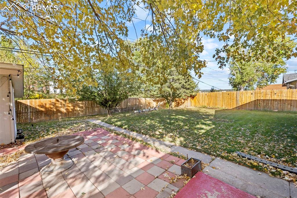 Image 23 of 30: Fenced backyard with a patio area