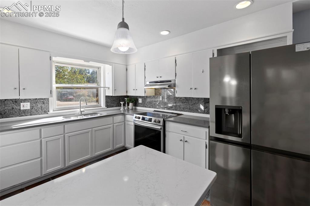 Image 6 of 30: Kitchen featuring stainless steel appliances, white cabinetry, backsplash,