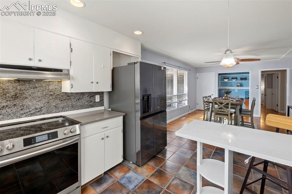 Image 7 of 30: Kitchen with appliances with stainless steel finishes, white cabinetry, und