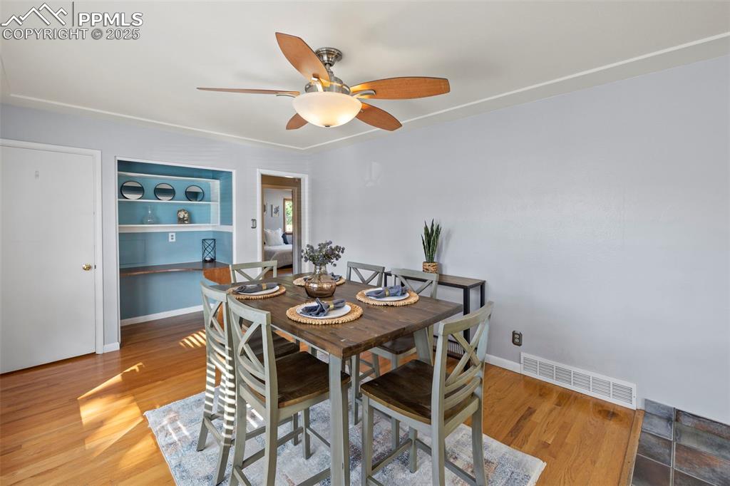 Image 8 of 30: Dining space with light wood finished floors, ceiling fan, and built in she