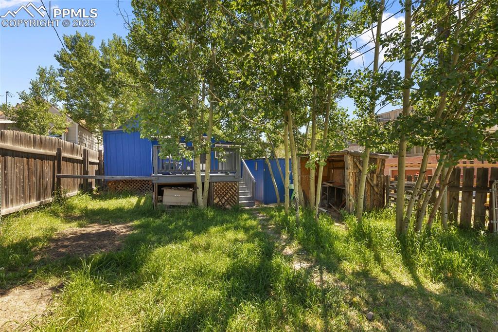 Image 8 of 36: this shot provides a great view of the deck, storage sheds and wooden fence
