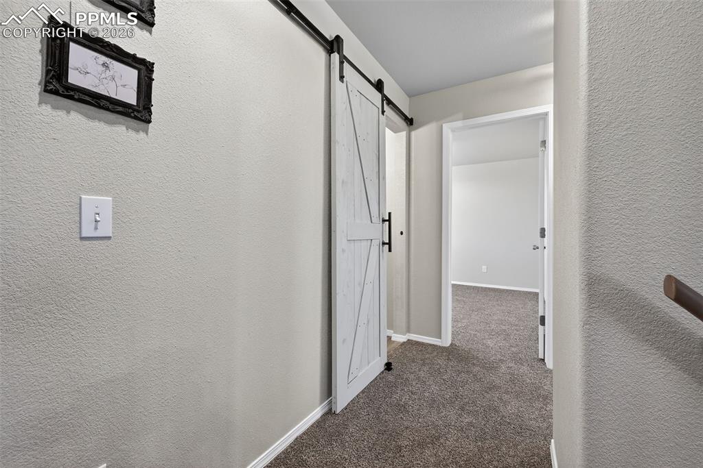 Image 29 of 50: The main hallway on the 2nd floor. A barn door entrance to this bathroom al
