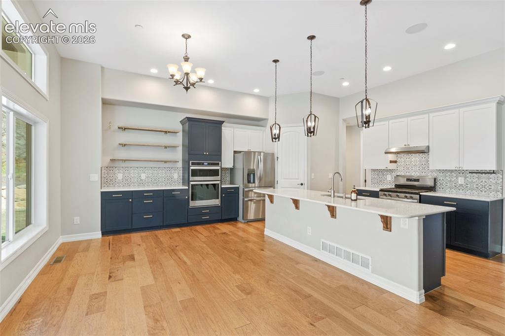 Image 14 of 47: Kitchen featuring a large central island with pendant lighting, stainless s