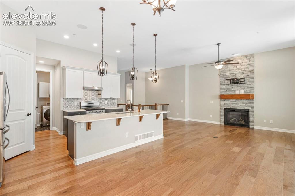 Image 15 of 47: Open-concept living area featuring a kitchen island with pendant lighting, 