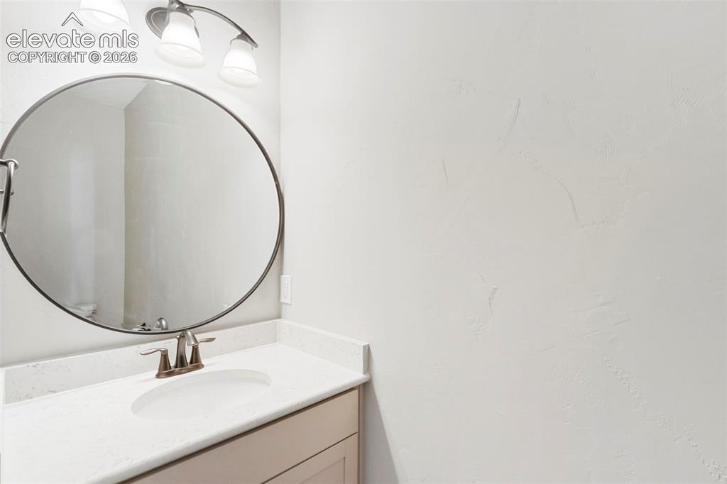 Image 17 of 47: Powder bath on main level. Vanity area featuring a circular mirror, brushed