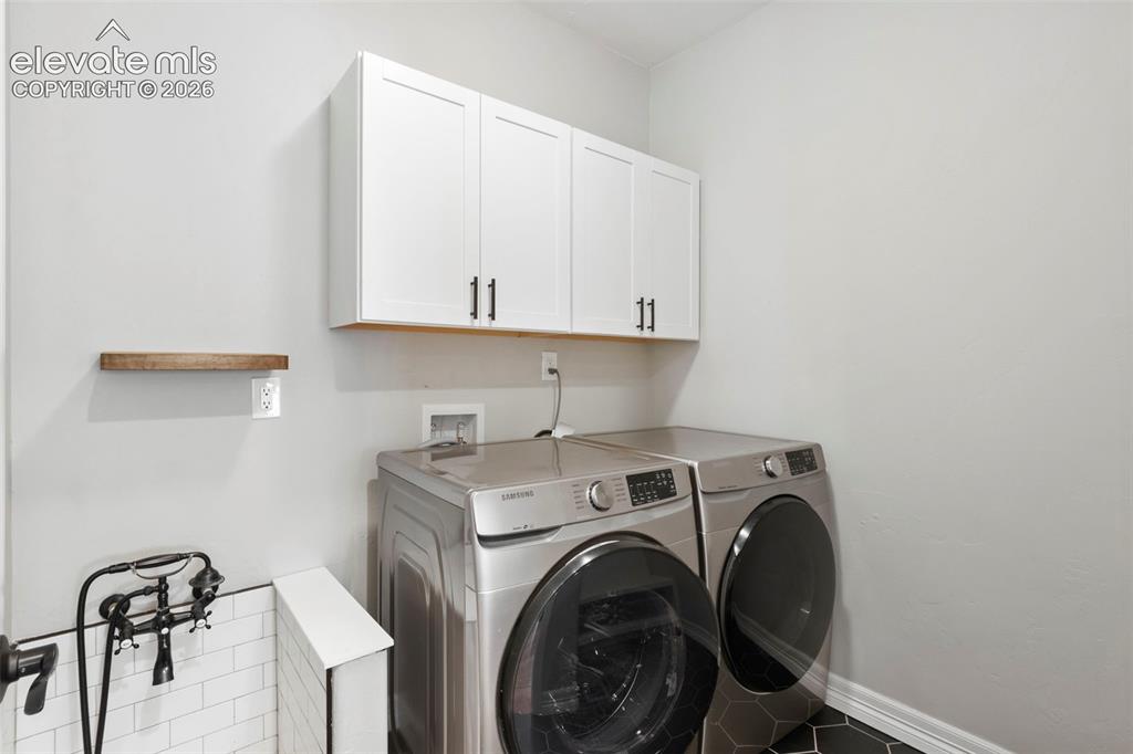 Image 18 of 47: Laundry area featuring front-load washer and dryer, white cabinetry with da
