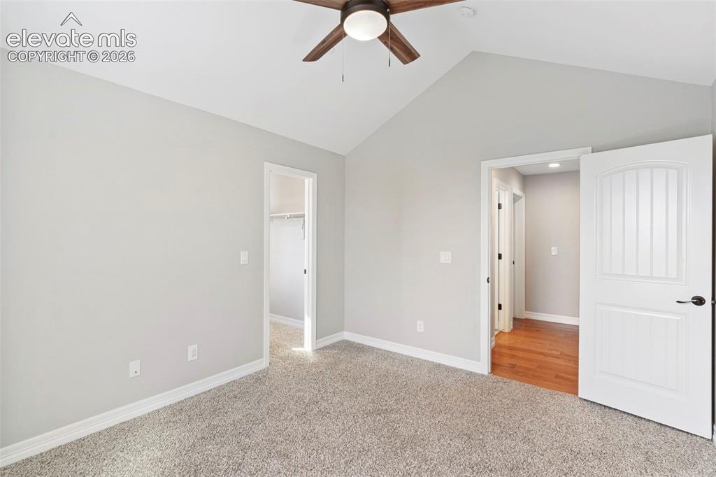 Image 20 of 47: Room featuring vaulted ceiling, wood-finish ceiling fan, gray carpet, and w
